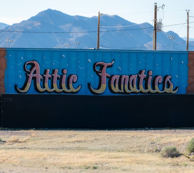 A mural with Attic Fanatics painted in colorful script, mountains and power lines in the background.