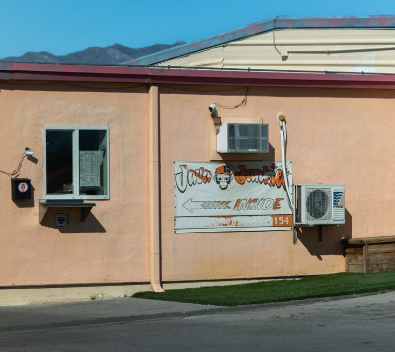 Peach-colored building with a sign reading “Java Junction Inside” and various air conditioning units attached.