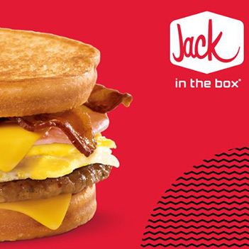 Close-up of a breakfast sandwich with egg, cheese, bacon, and sausage; Jack in the Box logo on red background.