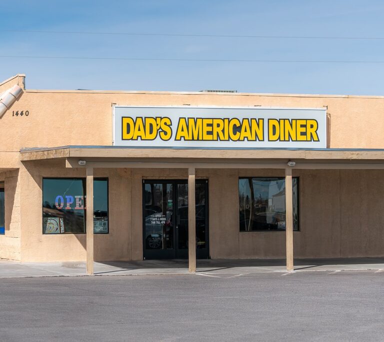 The front of Dads American Diner, with a yellow sign and glass entrance doors.