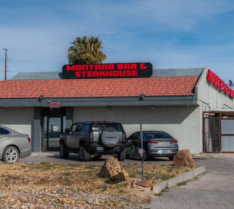 Montana Bar & Steakhouse building with cars parked in front and an open sign by the entrance.