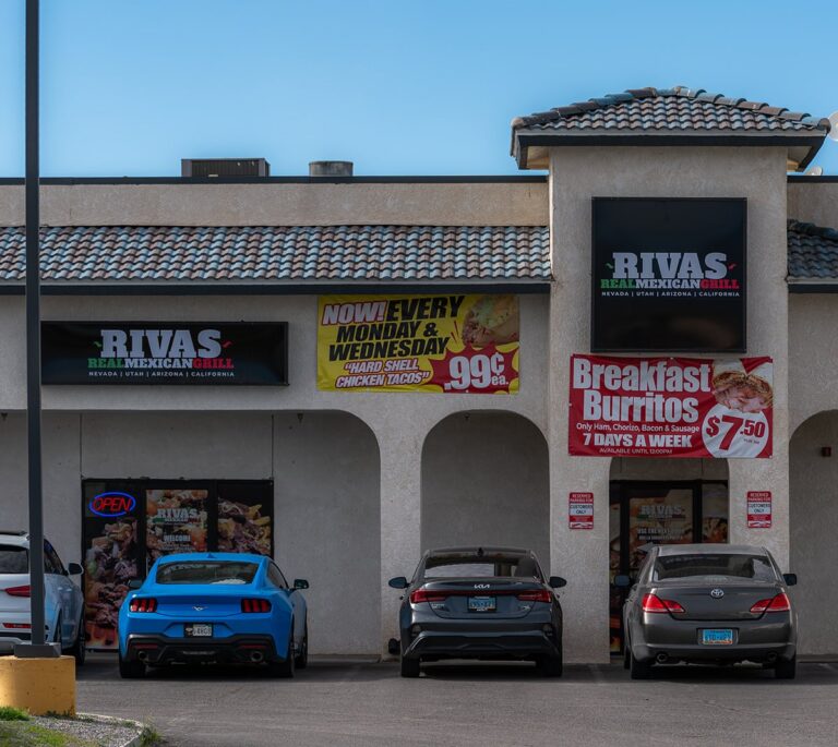 Four cars parked outside Rivas Mexican Grill, with banners advertising food specials on the building.