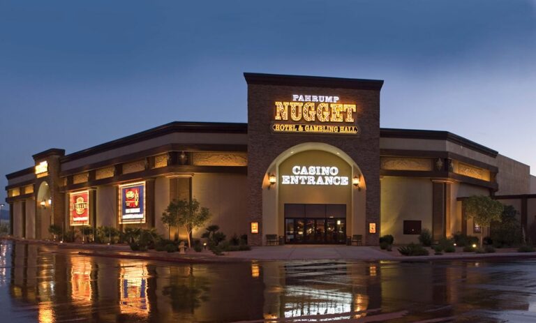 Exterior of Pahrump Nugget hotel and casino entrance at dusk, with lights reflecting on wet pavement.