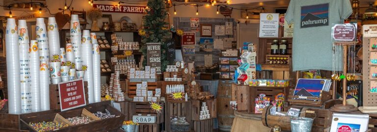 A cozy gift shop with stacked cups, t-shirts, soaps, local treats, and souvenirs on display.